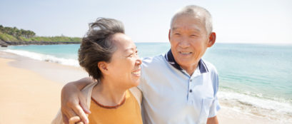Happy Asian Seniors Walking On The Beach